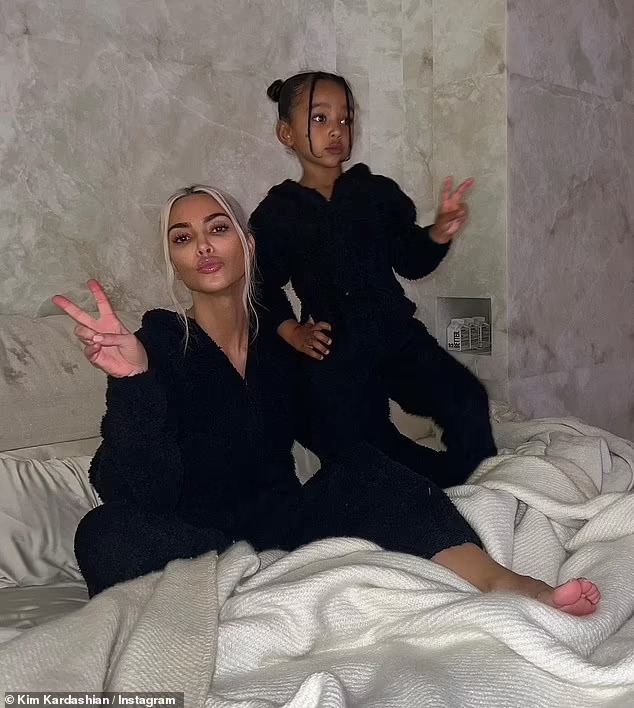 Kim Kardashian reveals she is trying to ‘enjoy every second’ with her children on summer break while sharing a snap of them sleeping in her bed