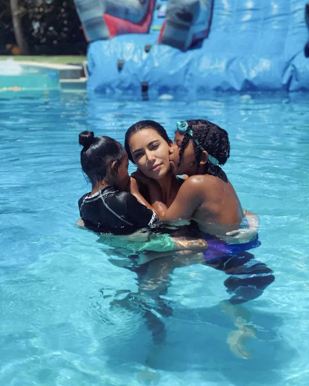 SWEET SUMMER Kim Kardashian gets kisses from Saint, 7, and Chicago, 5, as the trio swim in the pool and go on mᴀssive water slide