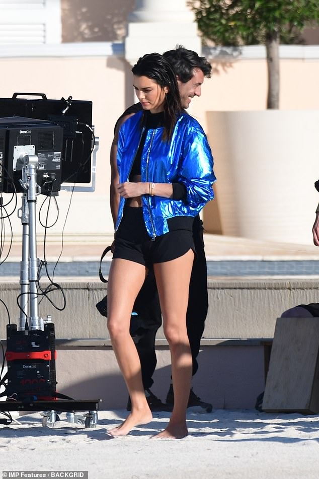 Kendall Jenner shows off her incredible physique in skimpy black crop top and shiny blue bomber jacket during beach pH๏τoshoot in St Tropez