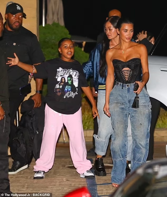 Kim Kardashian showcases her curves in a strapless top and stylish jeans as daughter North, 10, strikes a playful pose while leaving restaurant