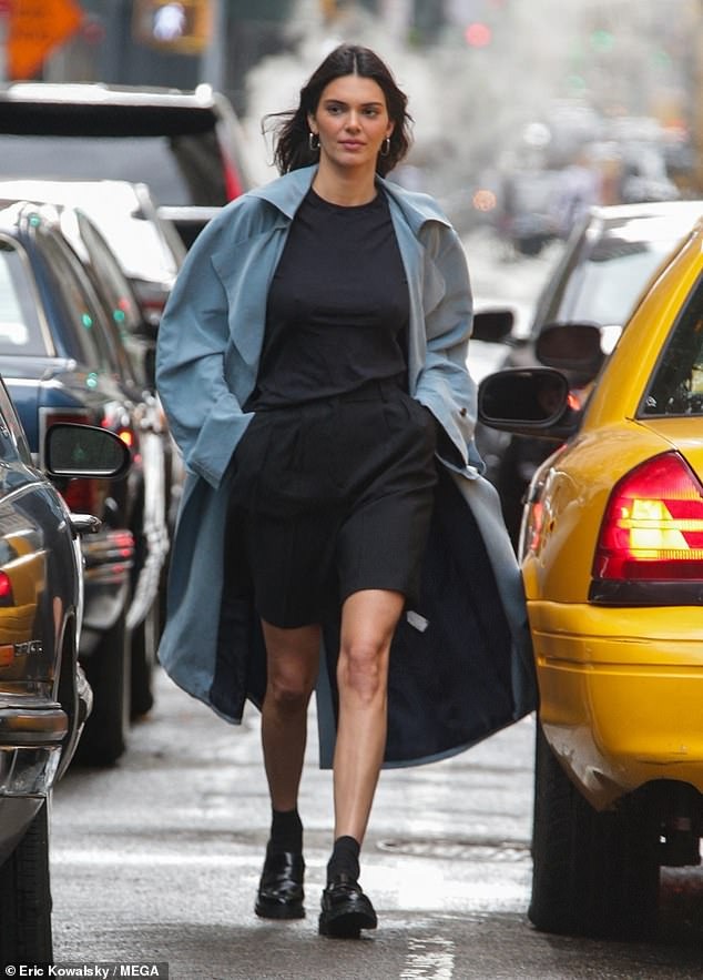 Kendall Jenner looks typically chic in a light blue trench coat and flashes her legs while posing confidently as she films new campaign in NYC